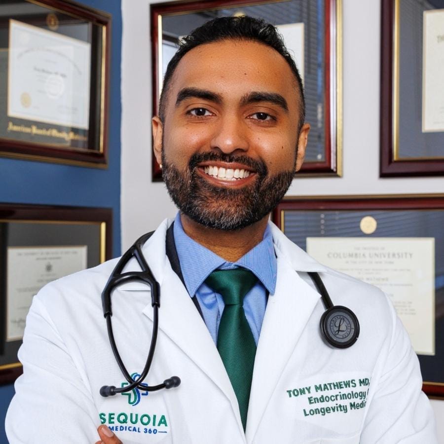 Dr. Tony Mathews, MD, MPH, Endocrinologist and Longevity Medicine specialist at Sequoia Medical 360, standing confidently in his office in front of wall of medical diploma's.